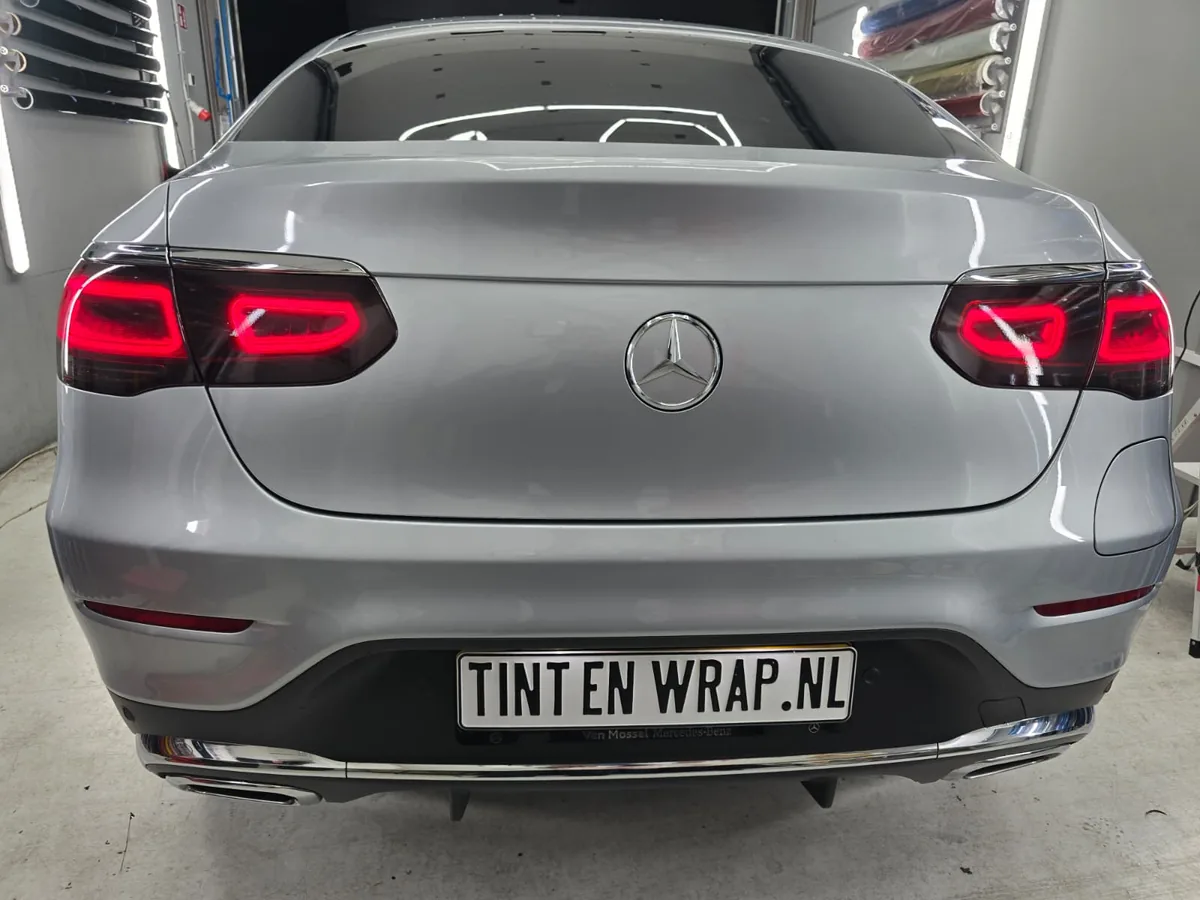 Zilvergrijze Mercedes CLE met rode achterlichten en TINT EN WRAP.NL-bord