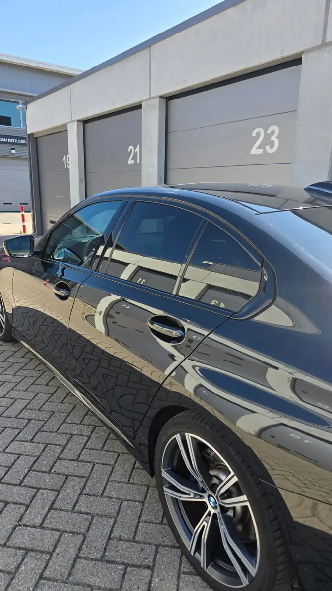 Donkerblauwe BMW 4-serie Gran Coupe met getinte zijruiten, gefotografeerd van de zijkant
