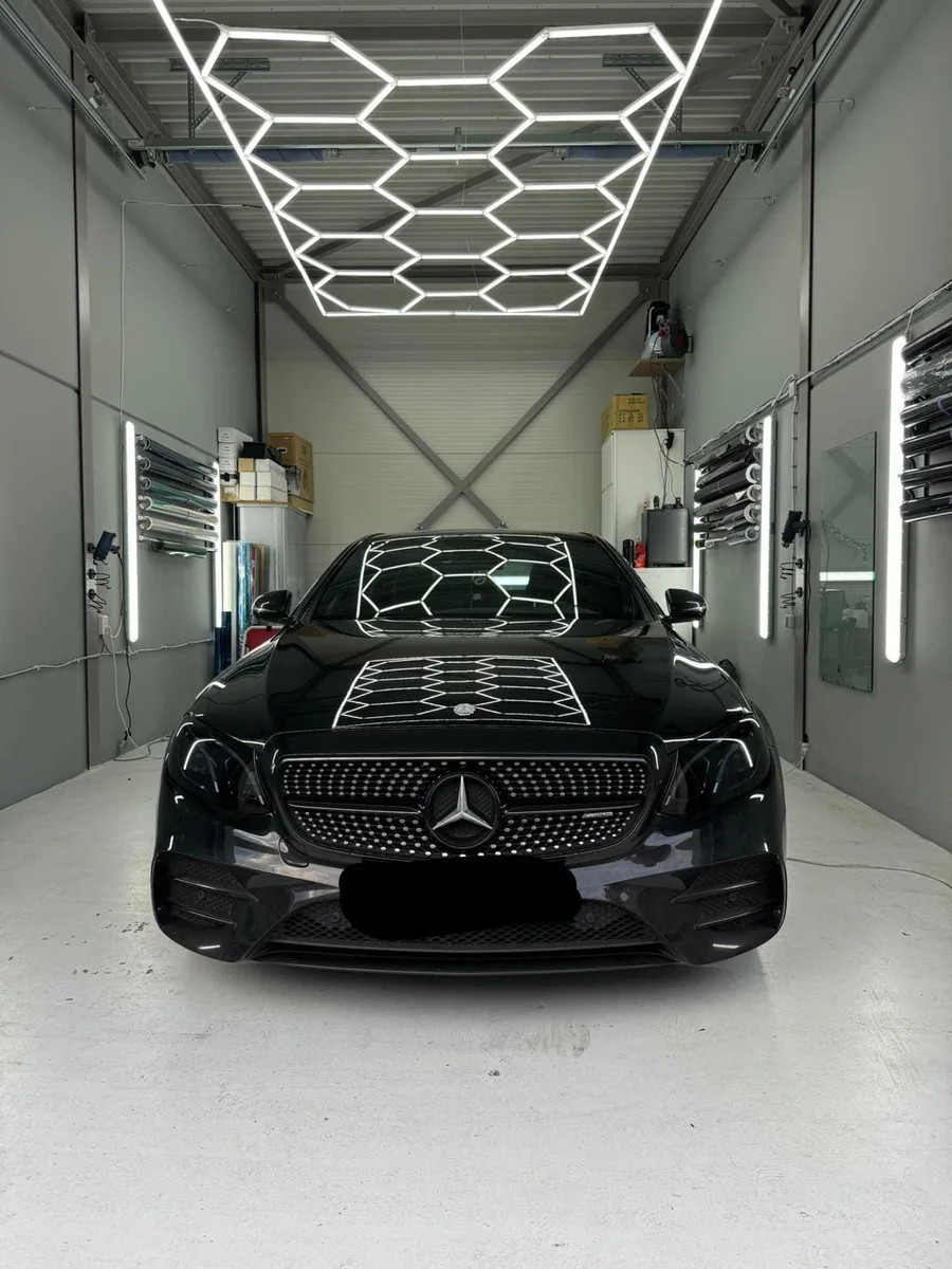 Zwarte Mercedes E-klasse met getinte voorruit, gefotografeerd van voren in de werkplaats