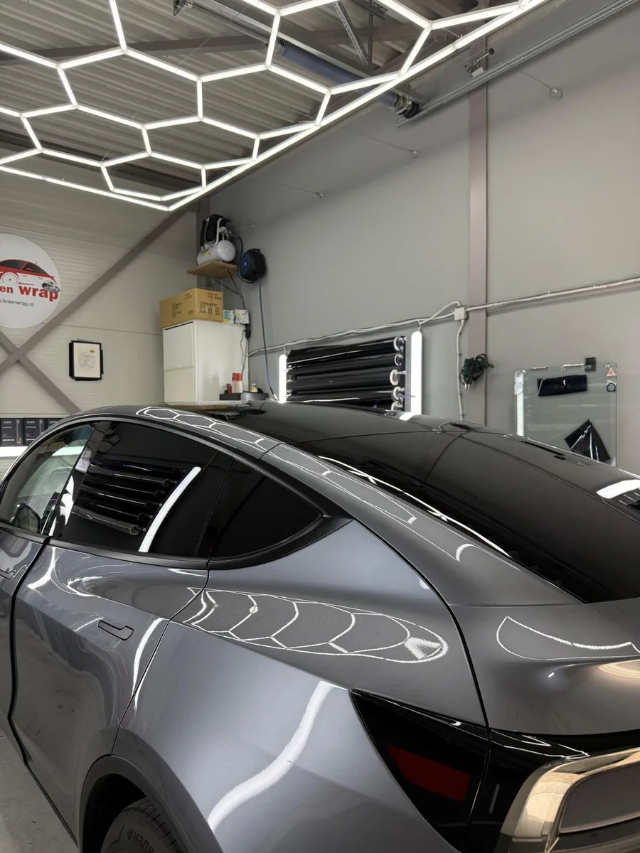 Getinte achterruit van een zilvergrijze Tesla in de werkplaats