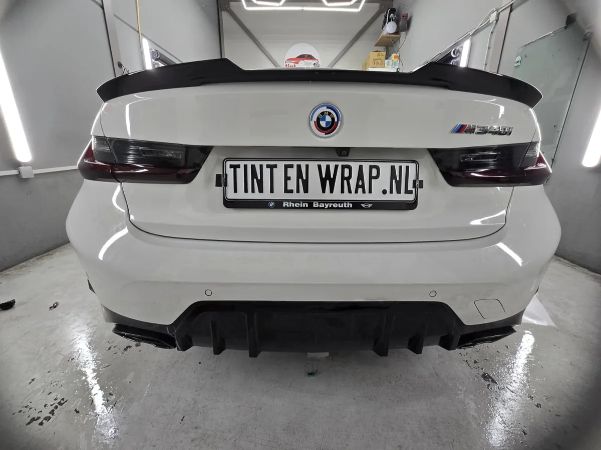 Witte BMW M3 met gesmokte achterlichten en donkere achterruit, gefotografeerd van achteren