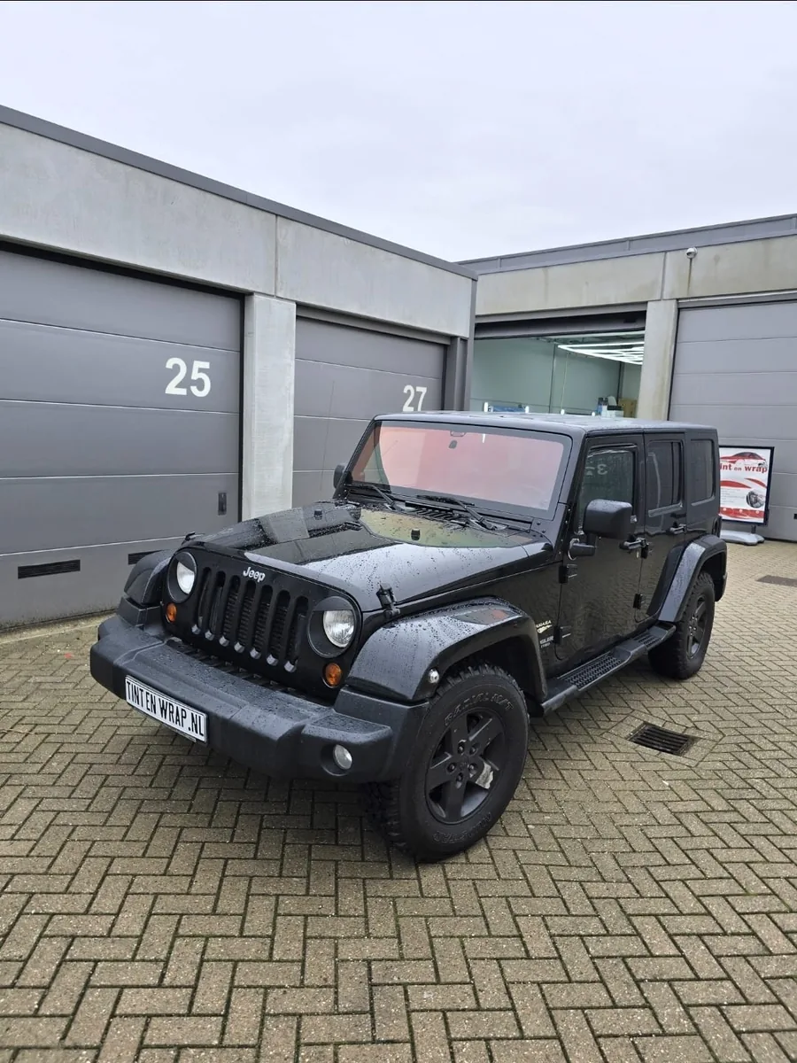 Zwarte Jeep Wrangler met getinte ruiten buiten de werkplaats