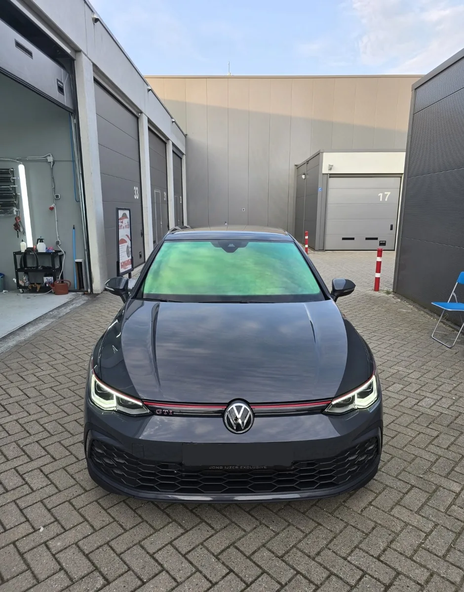 Grijze Volkswagen Golf GTI met getinte voorruit, gefotografeerd van voren
