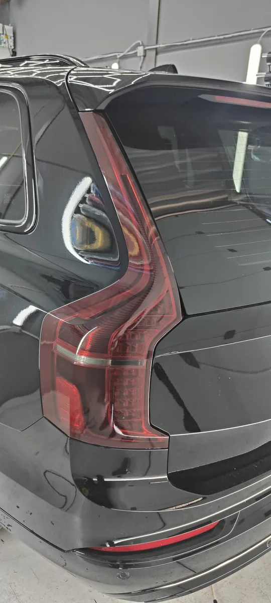 Detail van het achterlicht en de getinte achterruit van een zwarte Volvo