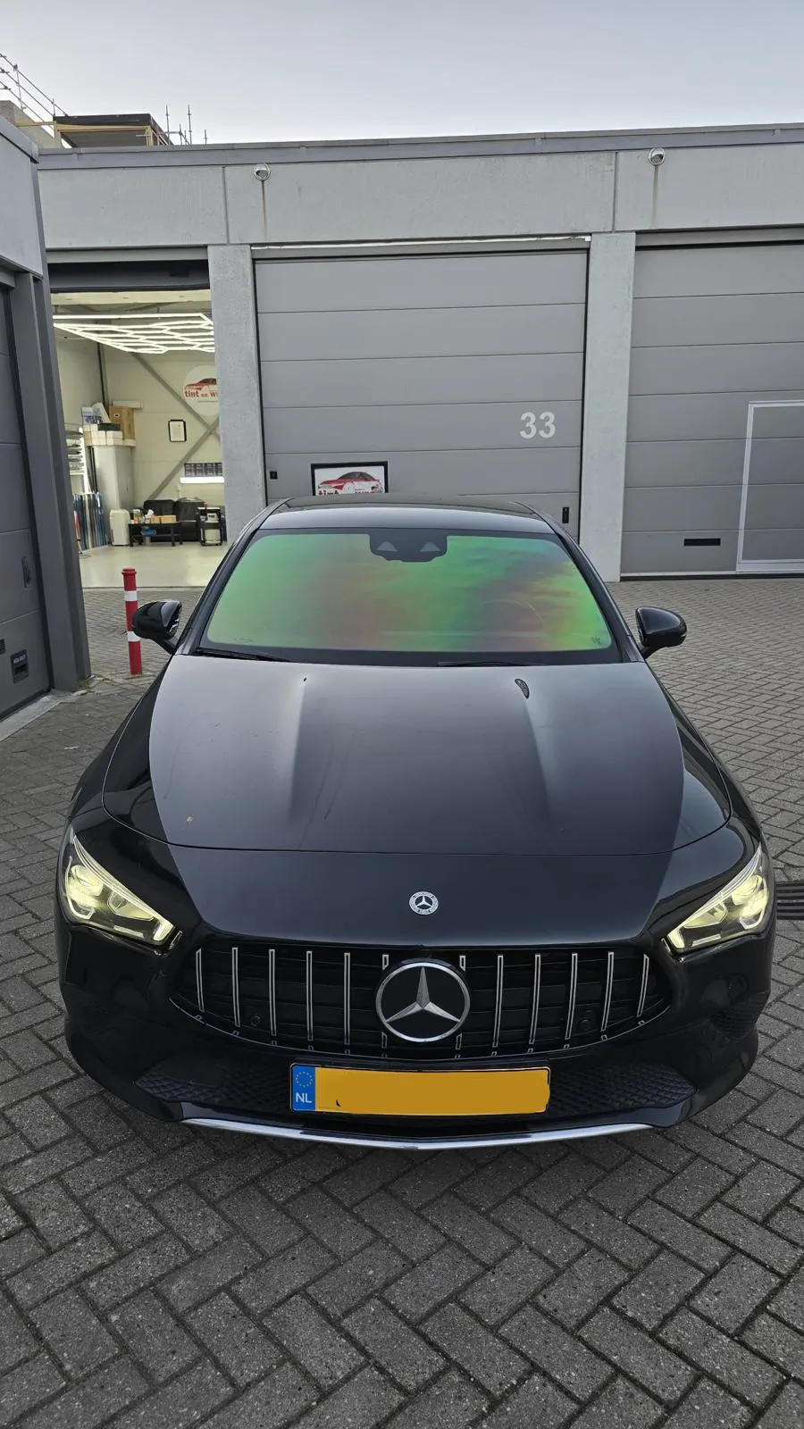 Zwarte Mercedes met groen reflecterende chameleon folie op de voorruit