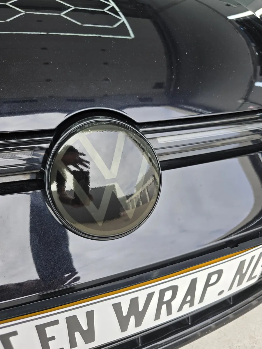 Gesmokt Volkswagen-logo op de grille boven een TINT EN WRAP.NL-kenteken